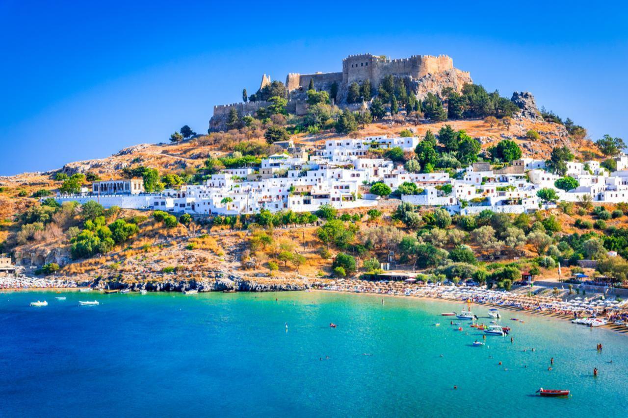 Lindos Acropolis rises above the whitewashed houses and beach in Rhodes, Greece, accessed August 21, 2025. (Adobe Stock Photo)