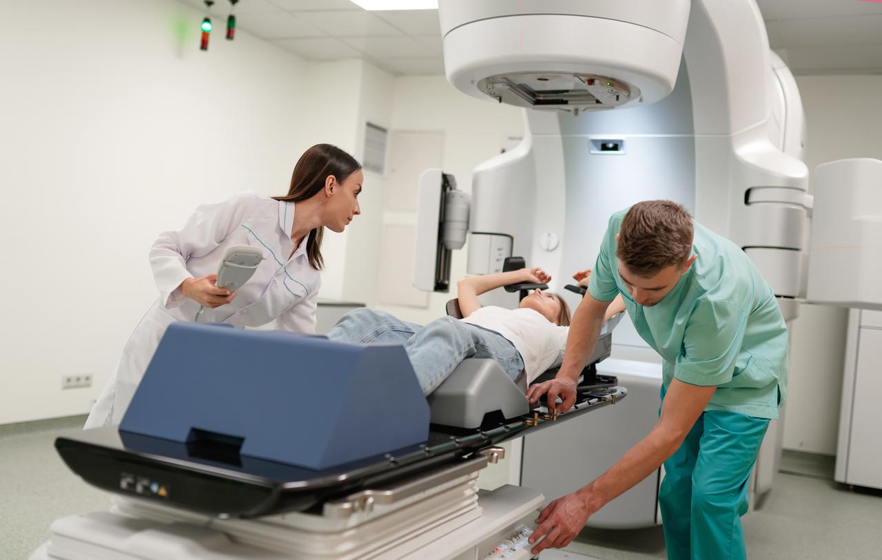 Two medical specialists position a patient for radiotherapy with the help of a linear accelerator machine. (Adobe Stock Photo)