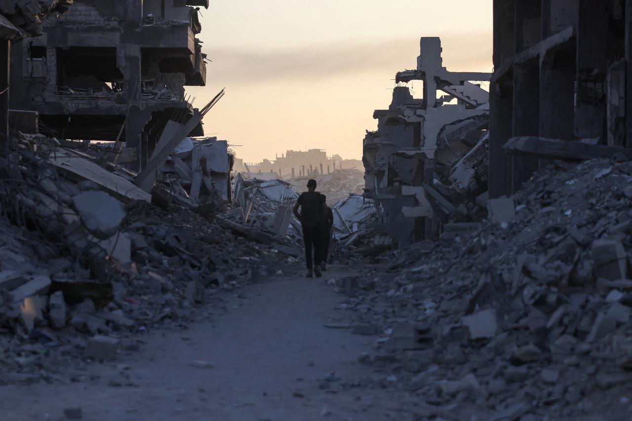 Men walk between piles of rubble in Saftawi neighbourhood, west of Jabalia in the northern Gaza Strip, on August 24, 2025. (AFP Photo)