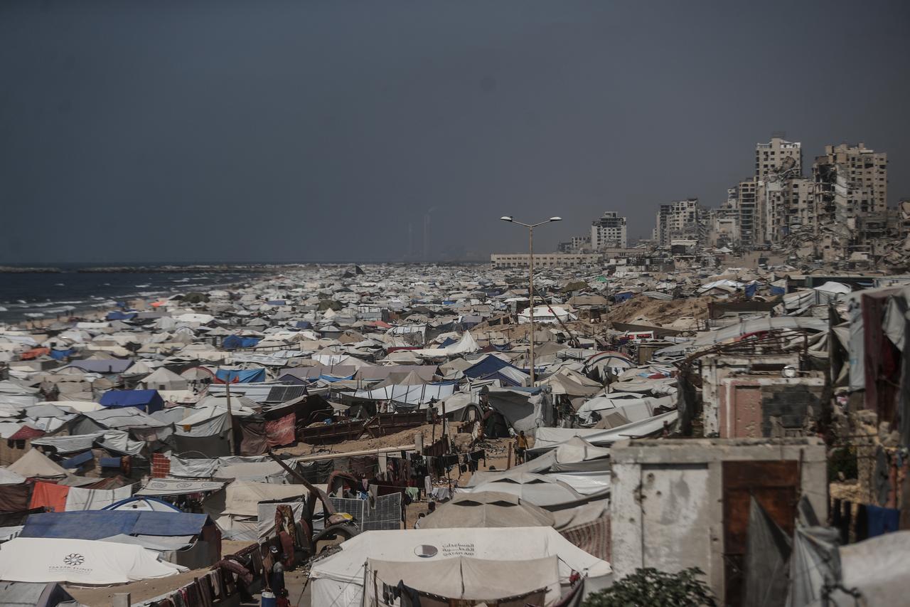 A view of the tent city along the shore of Gaza City, with buildings destroyed by the Israeli attacks in the background as Palestinians struggle to survive with limited shelter, food and basic necessities in Gaza City, Gaza on August 24, 2025. (AA Photo)
