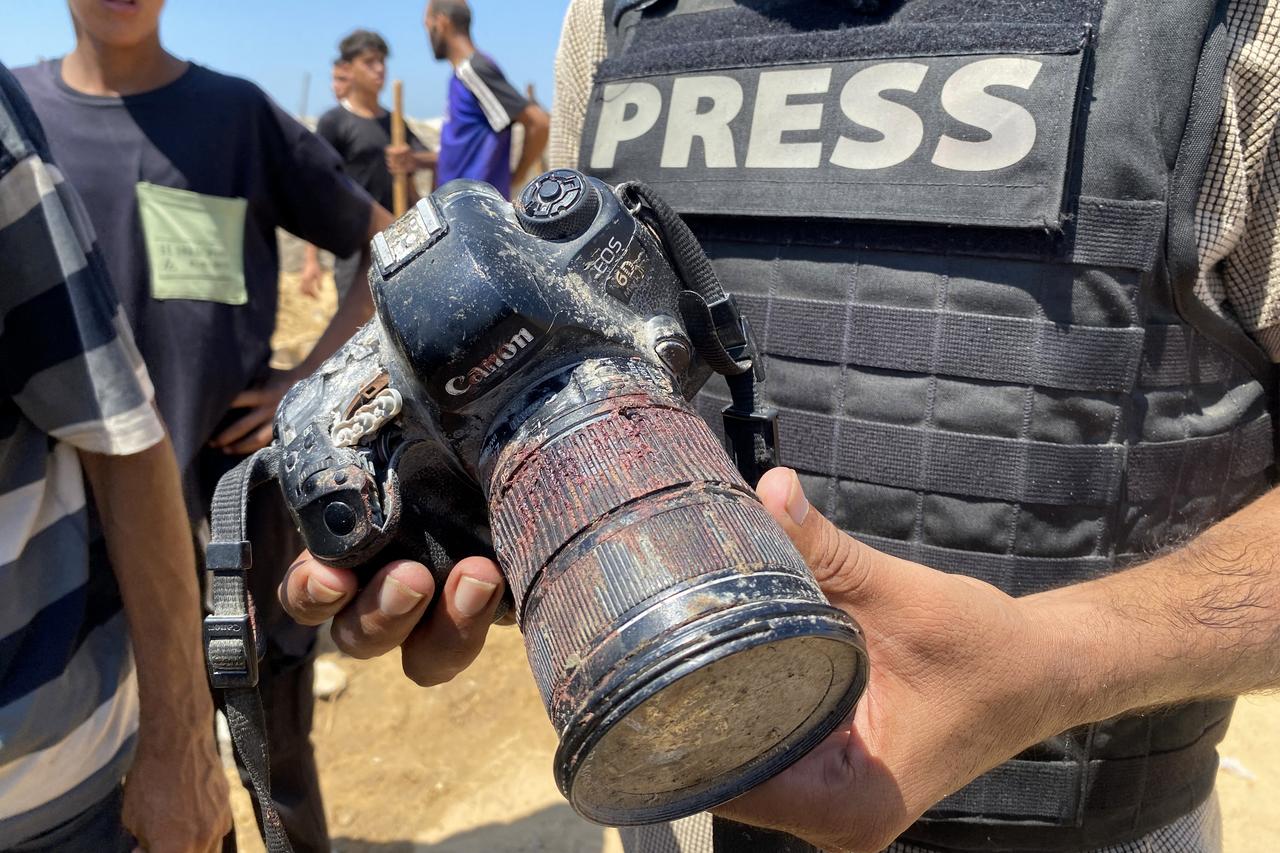 A journalist holds the blood-covered camera belonging to Palestinian photojournalist Mariam Dagga, a journalist who was killed in an Israeli strike, during her funeral on August 25, 2025. (AFP Photo)