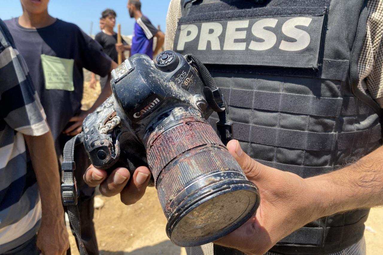 A journalist holds the blood-covered camera belonging to Palestinian photojournalist Mariam Dagga, a journalist who was killed in an Israeli strike, during her funeral on August 25, 2025. (AFP Photo)