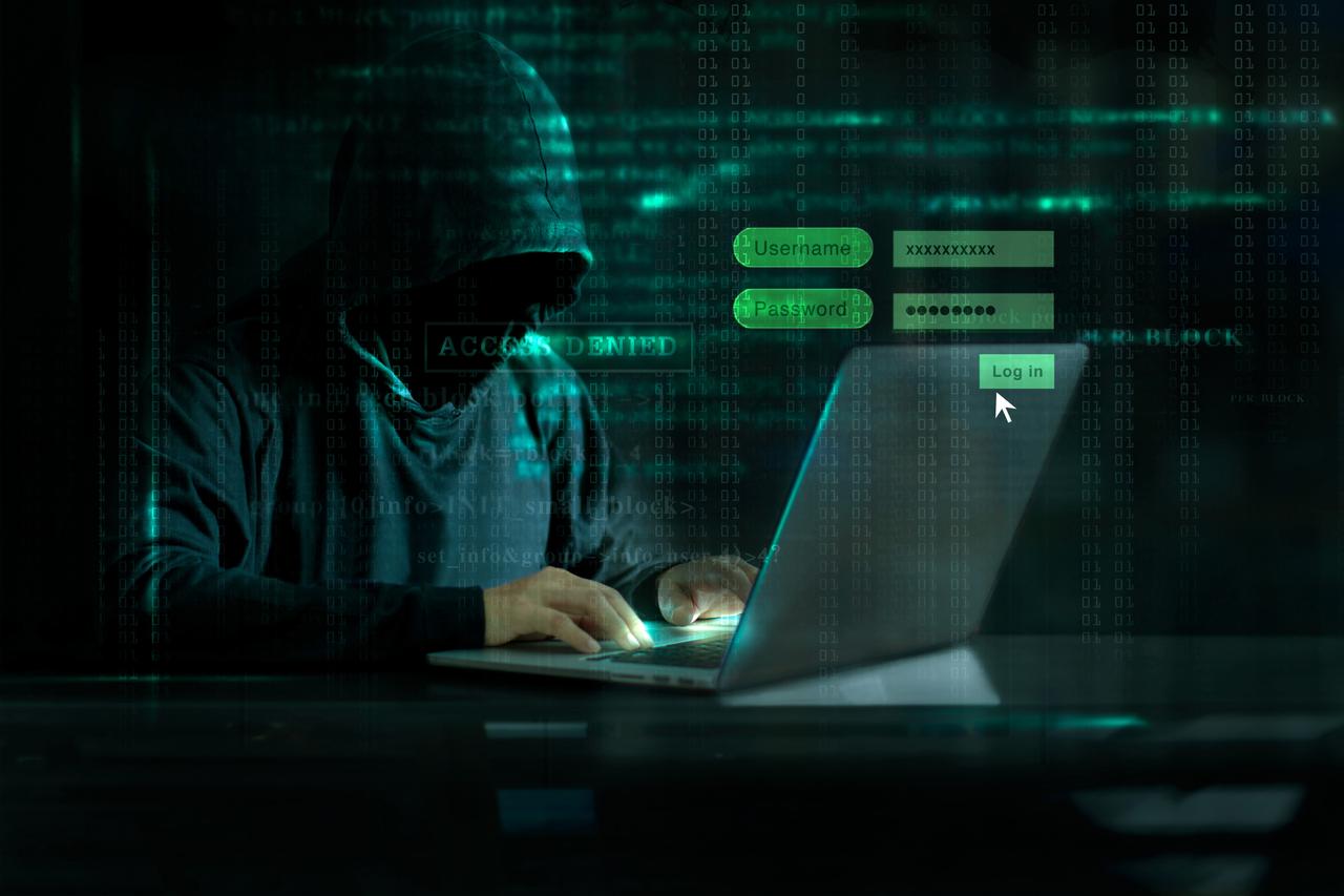 Hacker working on a laptop with a login screen. (Adobe Stock Photo)