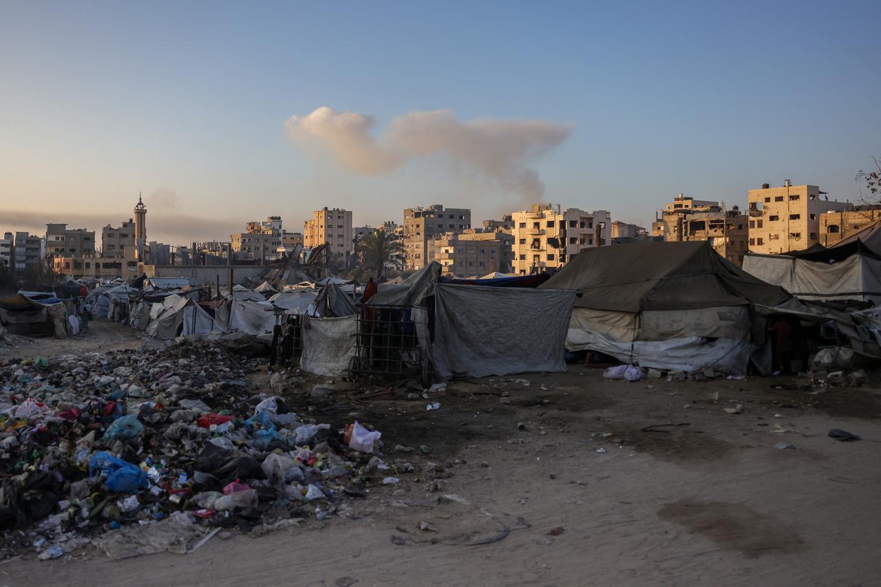 This picture shows shelters and rubbish in Jabalia, in the northern Gaza Strip, as smoke billows on the horizon during Israeli bombardment, August 25, 2025. (AFP Photo)