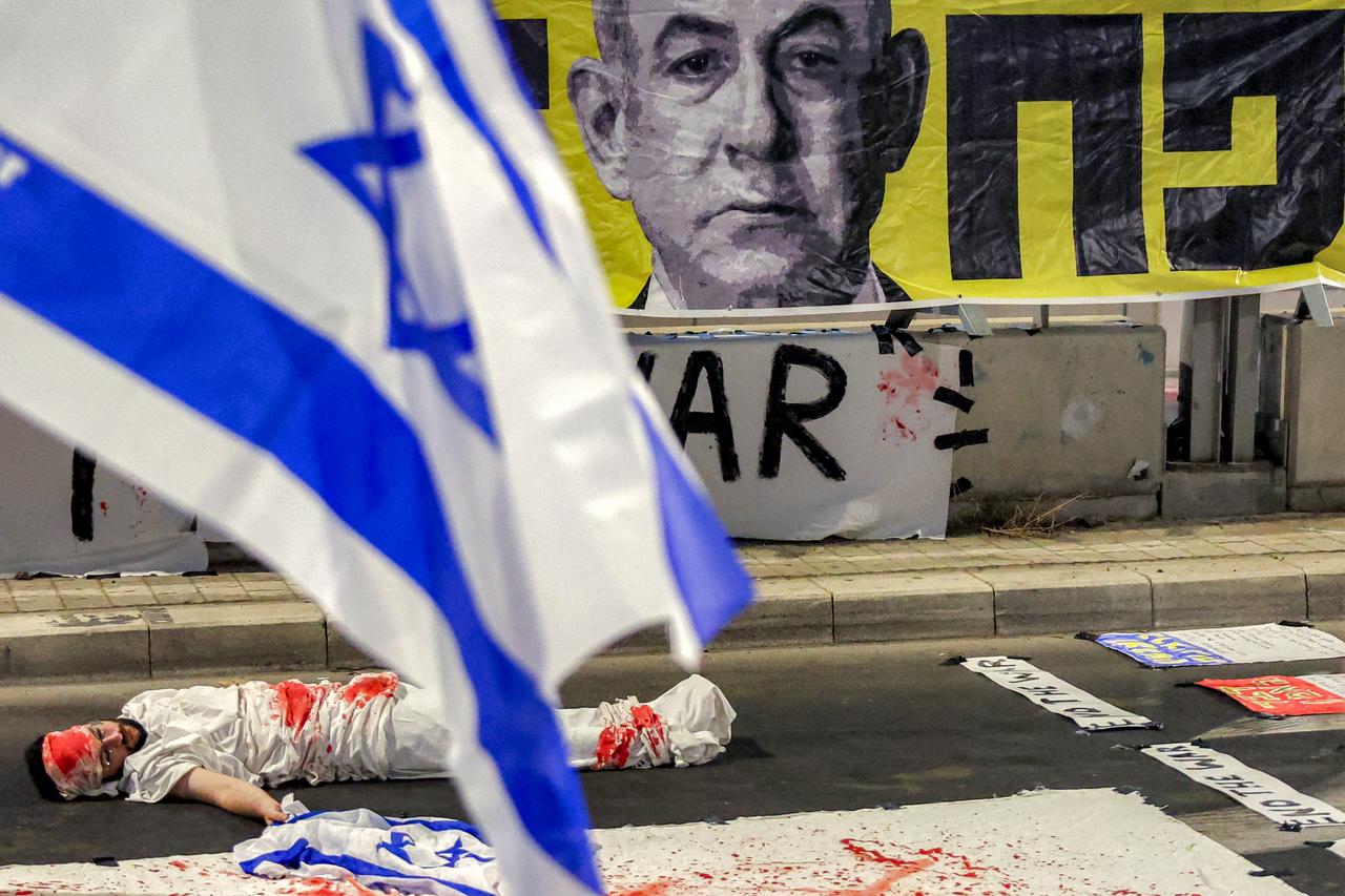 A demonstrator lies on the ground while depicting an Israeli hostage during an anti-government protest outside the Defense Ministry headquarters in Tel Aviv, August 23, 2025. (AFP Photo)