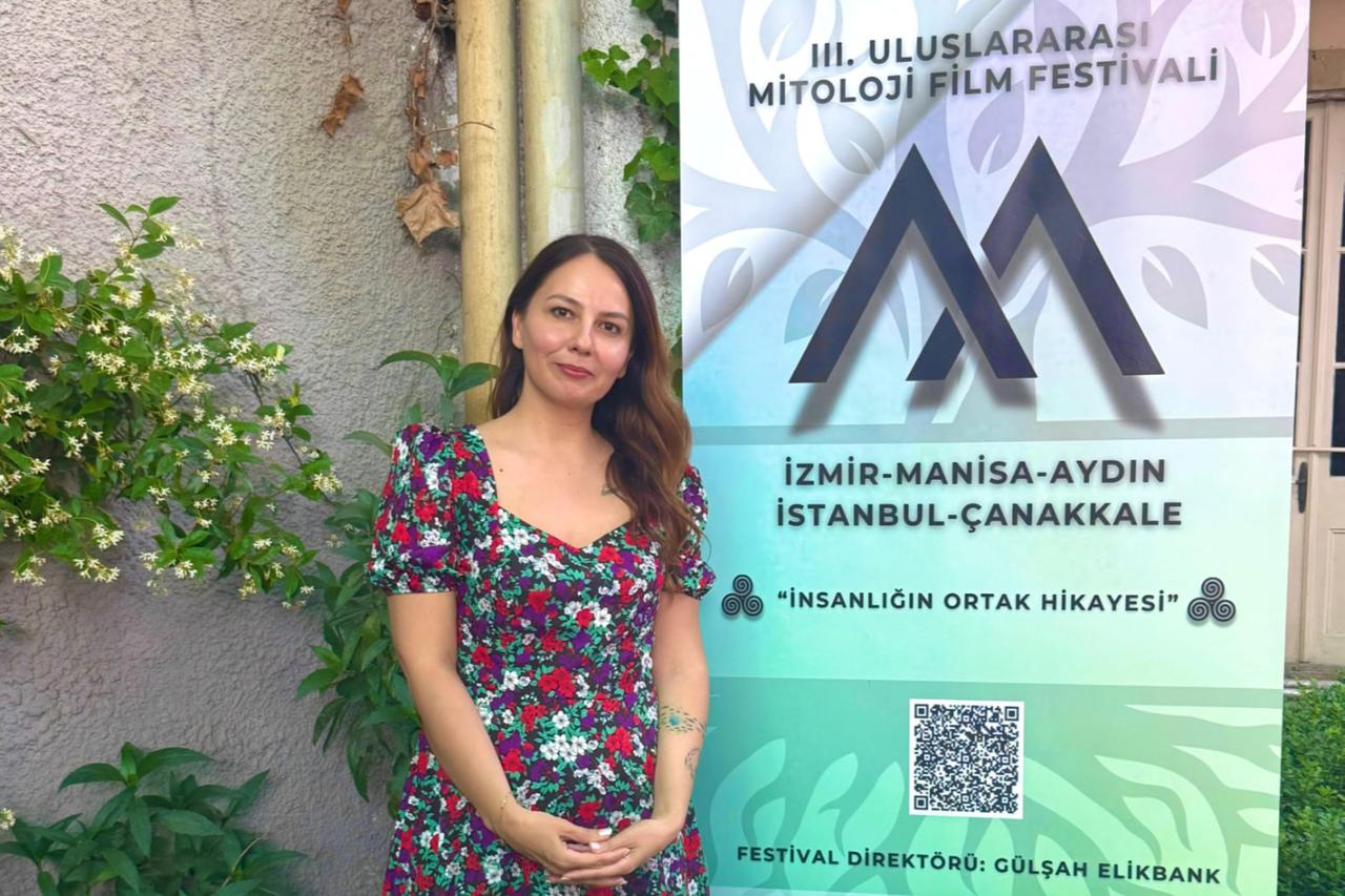 Gulsah Elikbank, director of the International Mythology Film Festival, stands beside the festival banner ahead of its third edition in Türkiye.(Photo via the International Mythology Film Festival)