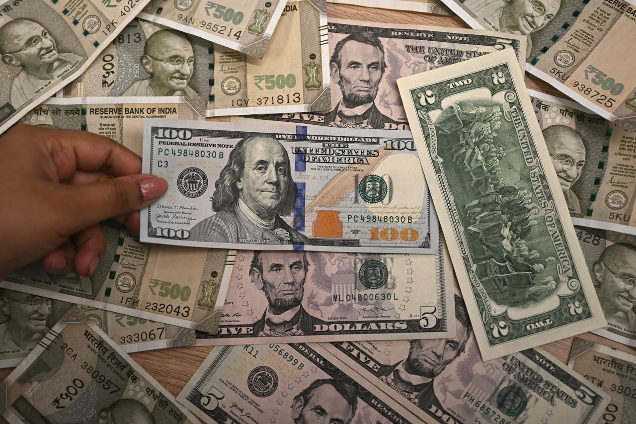 A foreign exchange employee displays Indian rupee and US dollar currency notes at an office in New Delhi on August 26, 2025. (AFP Photo)