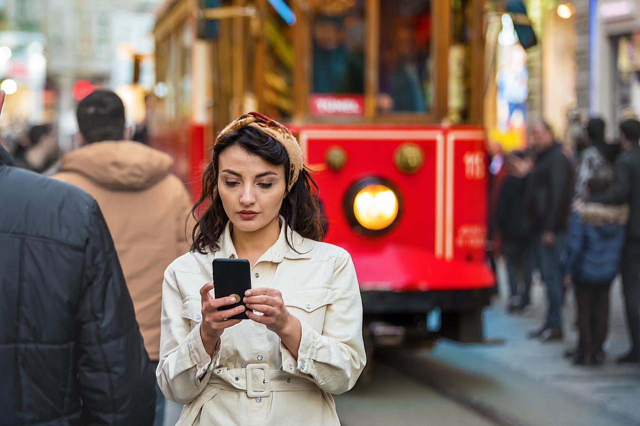 A woman uses her smartphone on Istiklal Street in Istanbul, Türkiye. (Adobe Stock Photo)
