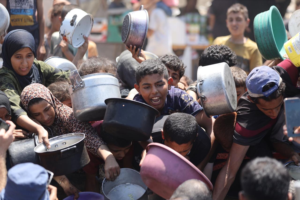 Palestinians, including children, who are struggling to access food due to Israel's blockade and ongoing attacks on the Gaza Strip, gather to receive hot meals distributed by the charity organization in Gaza City, Gaza on August 28, 2025. (AA Photo)