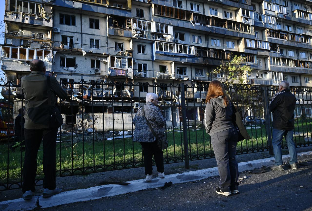 People stand in front of a residential building damaged during a large-scale Russian drone and missile attack on Kyiv on August 28, 2025. (AFP Photo)