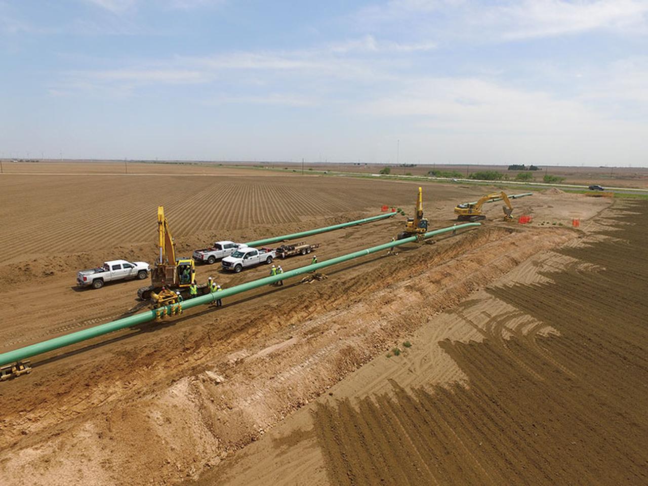 Construction crews install sections of a natural gas pipeline across farmland in the U.S. (Photo via pgjonline.com)