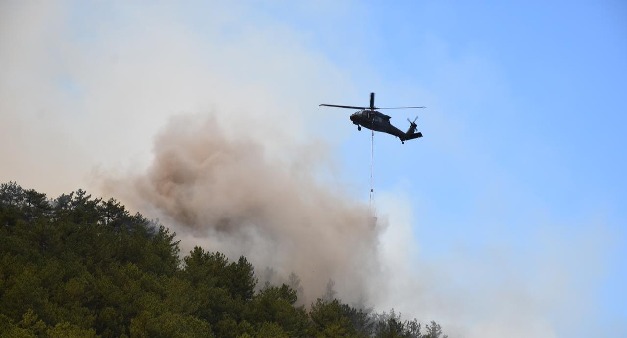 Firefighters continued battling a forest fire from the ground and air in Seyitgazi district, Eskisehir, Türkiye, as a helicopter dropped water amid billowing smoke, July 22, 2025. (AA Photo)