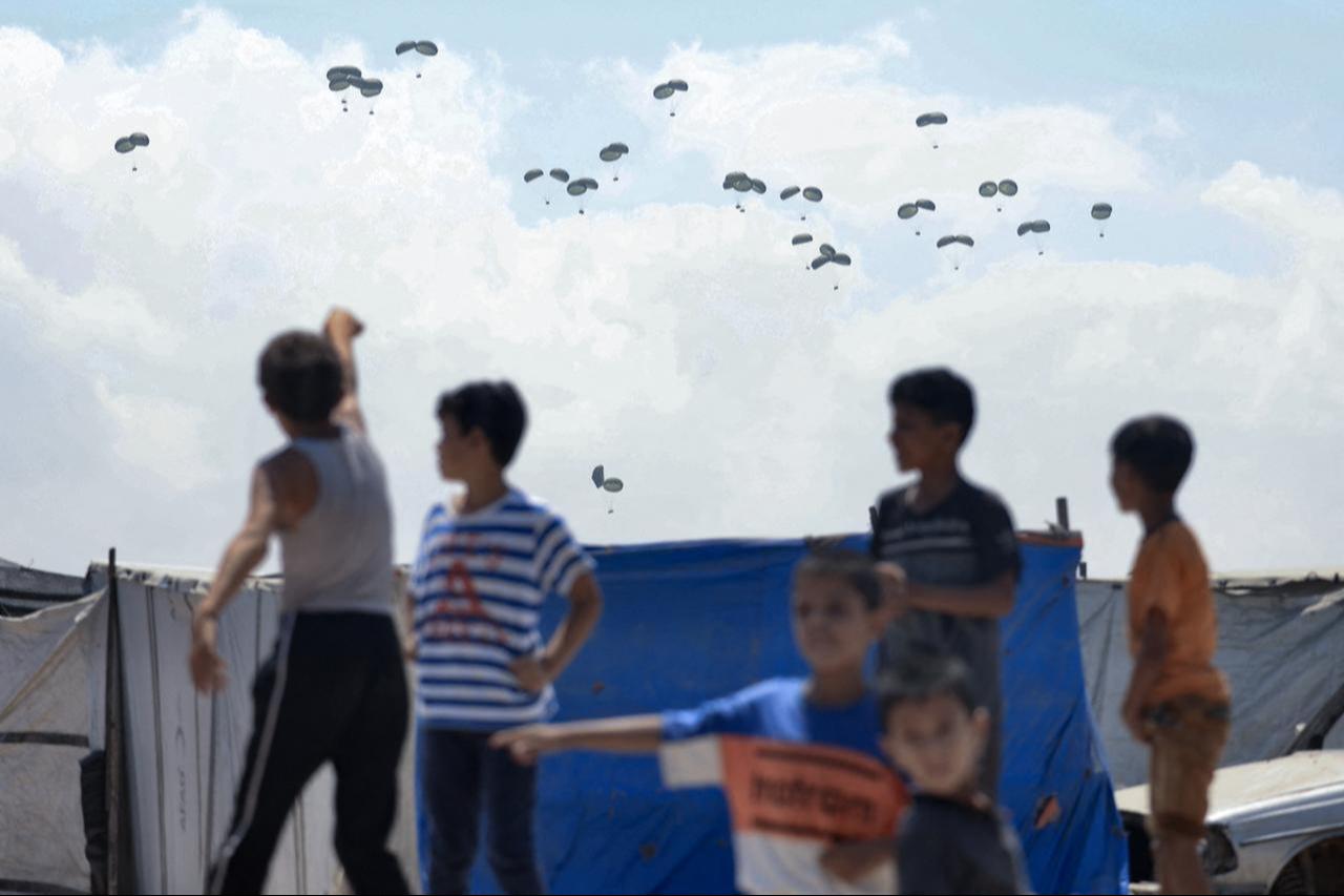 Children watch as food parcels are airdropped in Rafah in the southern Gaza Strip, August 2, 2025. (AFP Photo)