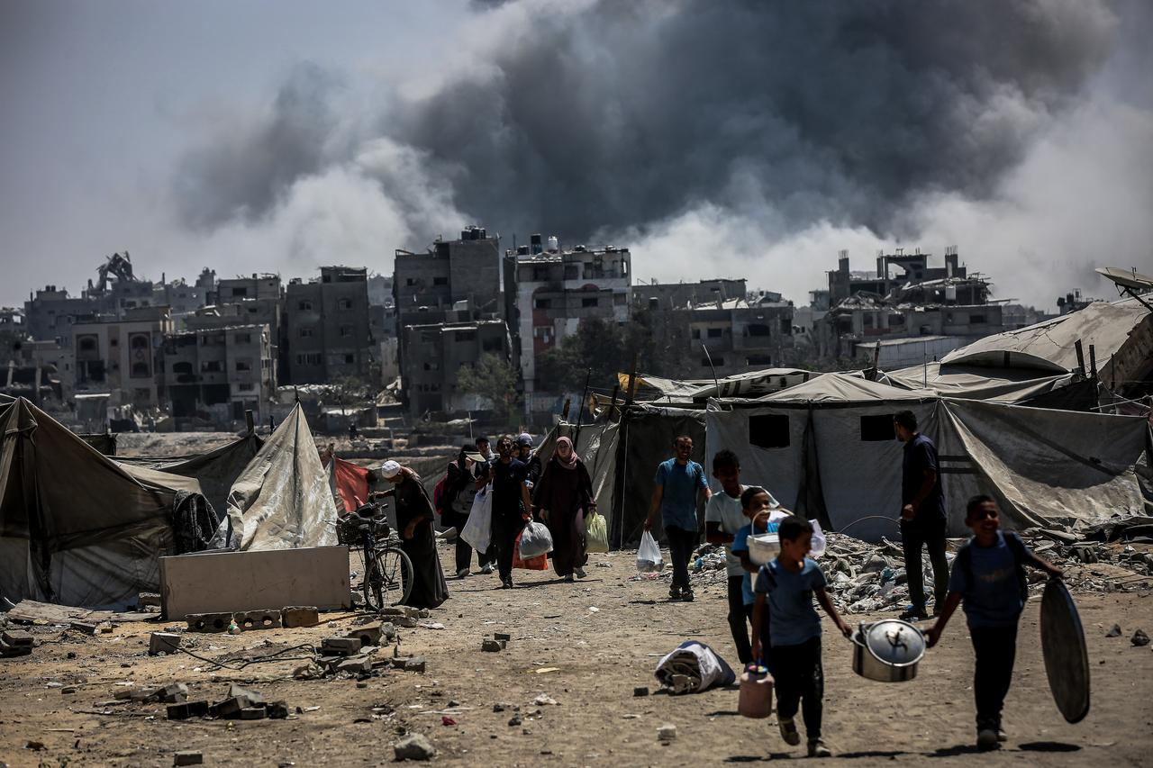 Smoke rises as Palestinians flee with their belonging after Israeli forces carried out strikes on the En-Nazla area of Jabalia and the Sheikh Radwan neighborhood in northern Gaza on August 30, 2025. (AA Photo)