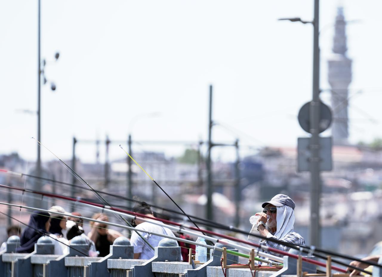 A fisherman drinks water to cool off during scorching hot weather in Istanbul, Türkiye on July 31, 2025. (AA Photo)