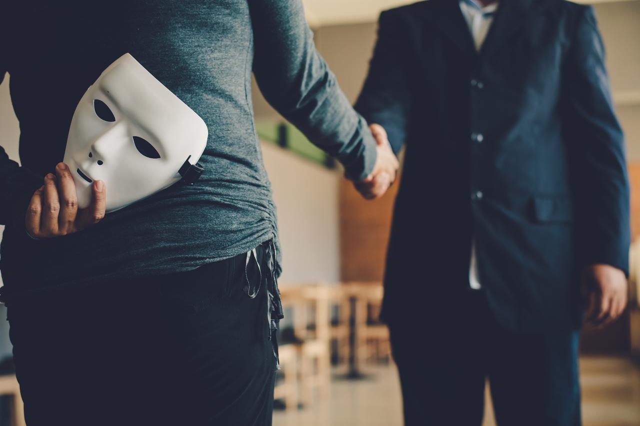 Man holding a mask behind his back while shaking hands with another, accessed on Aug. 5, 2025. (Adobe Stock Photo)