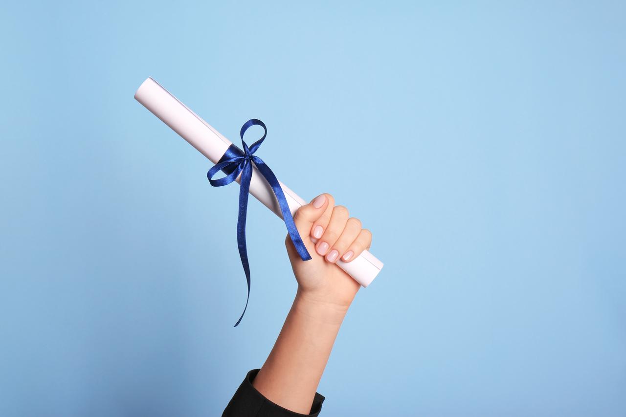 A diploma held high with blue ribbon around it, accessed on Aug. 5, 2025. (Adobe Stock Photo)