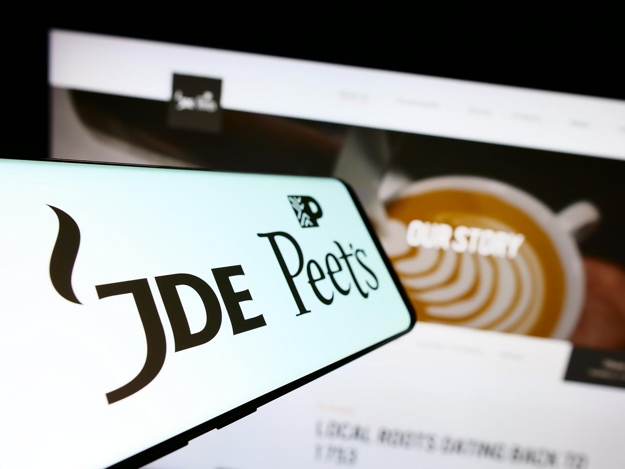 A smartphone displays the logo of Dutch beverage company JDE Peet’s NV in front of its official website in Stuttgart, Germany, August 5, 2023. (Adobe Stock Photo)