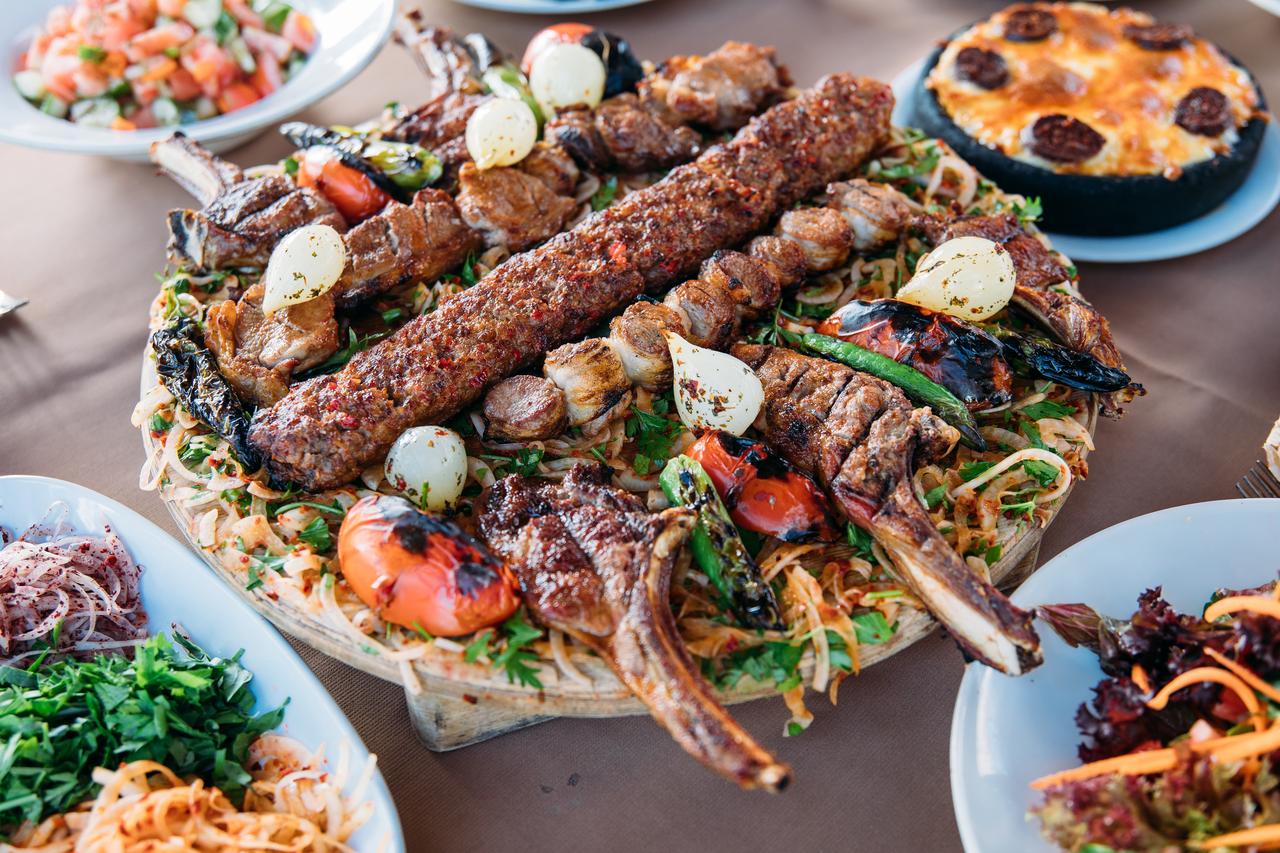 Traditional Turkish Adana kebab or kebap meat food, appetizers, raki and salgam on table from top view in turkish restaurant.(Photo by Adope Stock) .