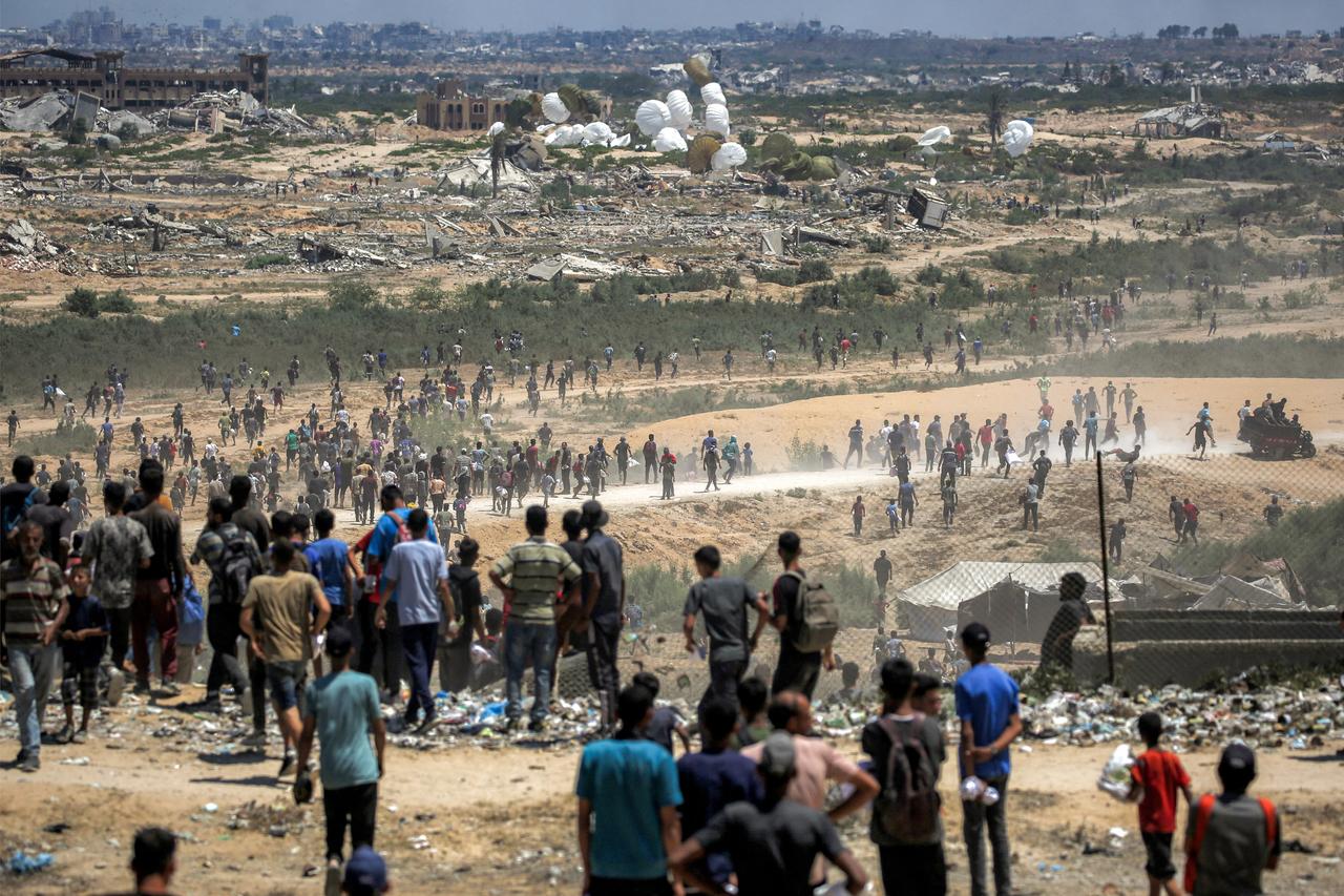 Palestinians rush to scene as air pallets, carrying humanitarian aid, parachute down after being dropped from a military plane over Nuseirat in central Gaza Strip on August 5, 2025. (AFP Photo)