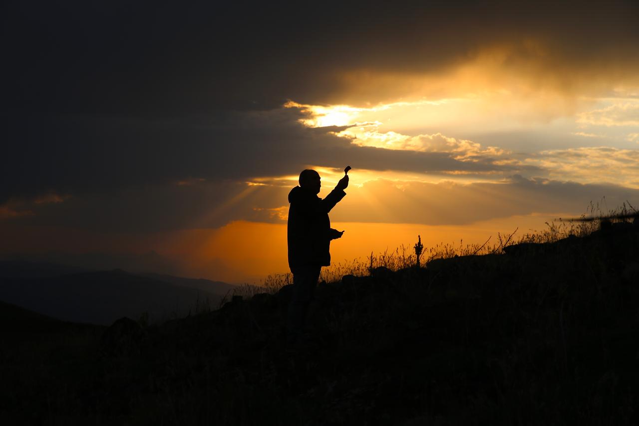 A man is silhouetted against the setting sun on a hill in Bingol, where 64-year-old Abdullah Kus displays a collection of ammunition and war relics he found from the Ottoman-Russian War of 1916–1917, including bullets, shrapnel, and horseshoes, which he has gathered over the years in Bingol, Türkiye, August 4, 2025. (AA Photo)
