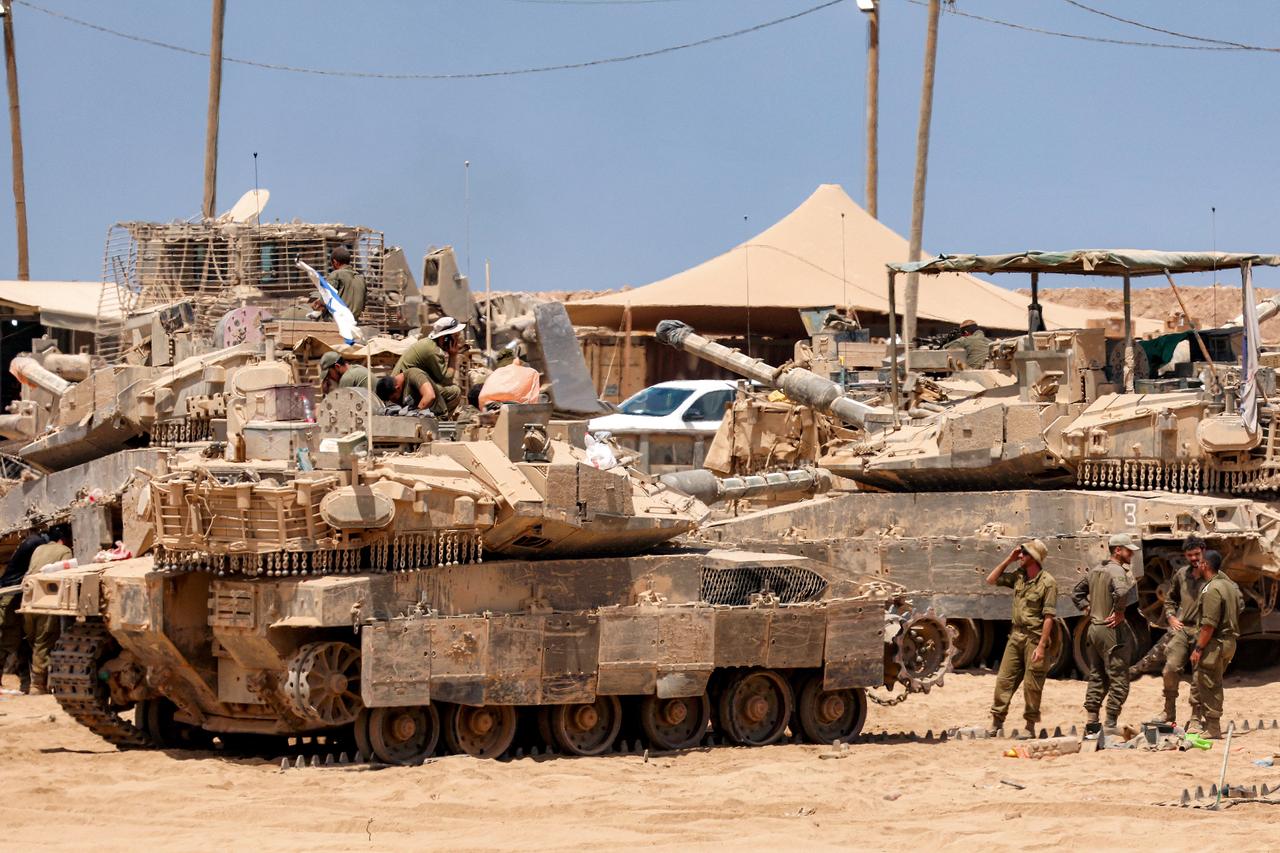 Israeli army soldiers perform maintenance tasks on a main battle tank positioned near the border with the Gaza Strip in southern Israel on August 5, 2025. (AFP Photo)