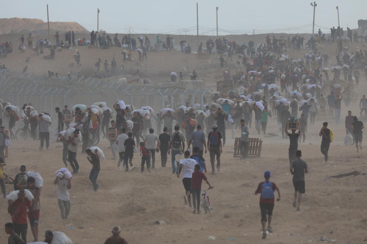 Displaced Palestinians struggling with hunger flock to an aid distribution point set up in the Netzarim Corridor in hopes of receiving limited humanitarian aid in Deir al Balah, Gaza on August 08, 2025. (AA Photo)