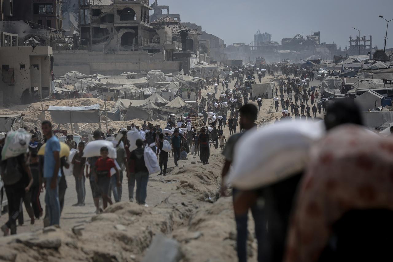 Palestinians struggling with severe food shortages amid ongoing Israeli attacks and blockade gather near the Zikim Crossing to receive limited aid supplies in northwestern Gaza on August 08, 2025. (AA Photo)