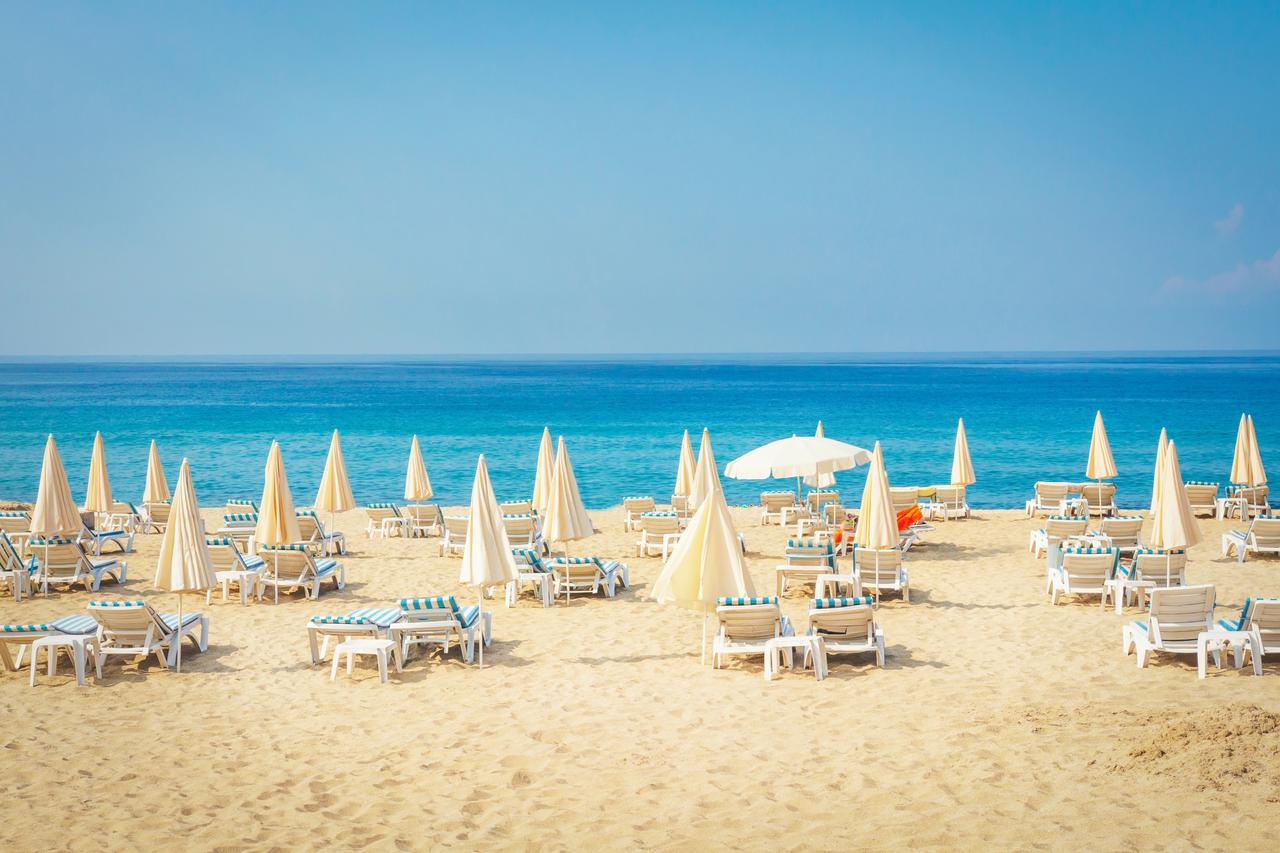Sun loungers and umbrellas arranged on a sandy beach in Antalya, Türkiye. (Adobe Stock Photo)