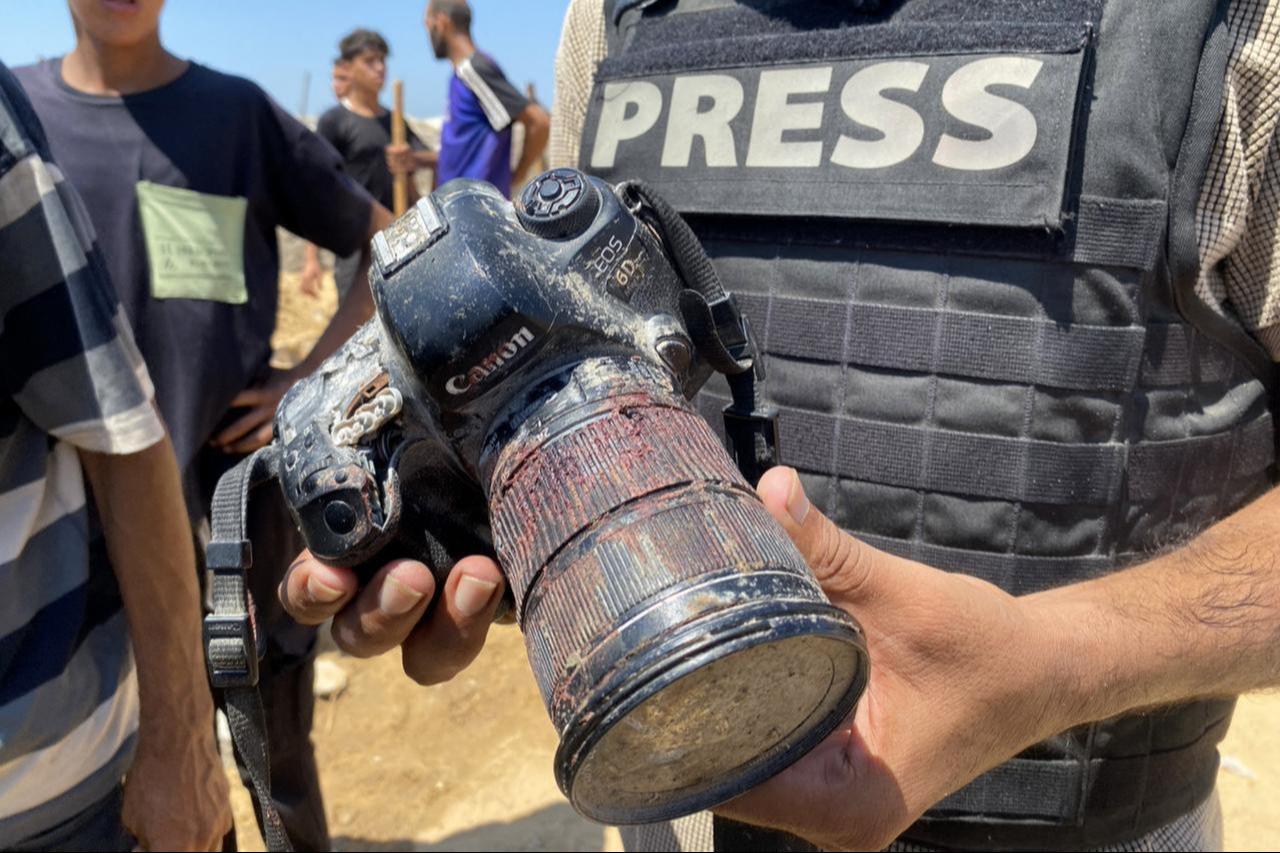 A journalist holds the blood-covered camera belonging to Palestinian photojournalist Mariam Dagga, a journalist who was killed in an Israeli strike, during her funeral, August 25, 2025. (AFP Photo)