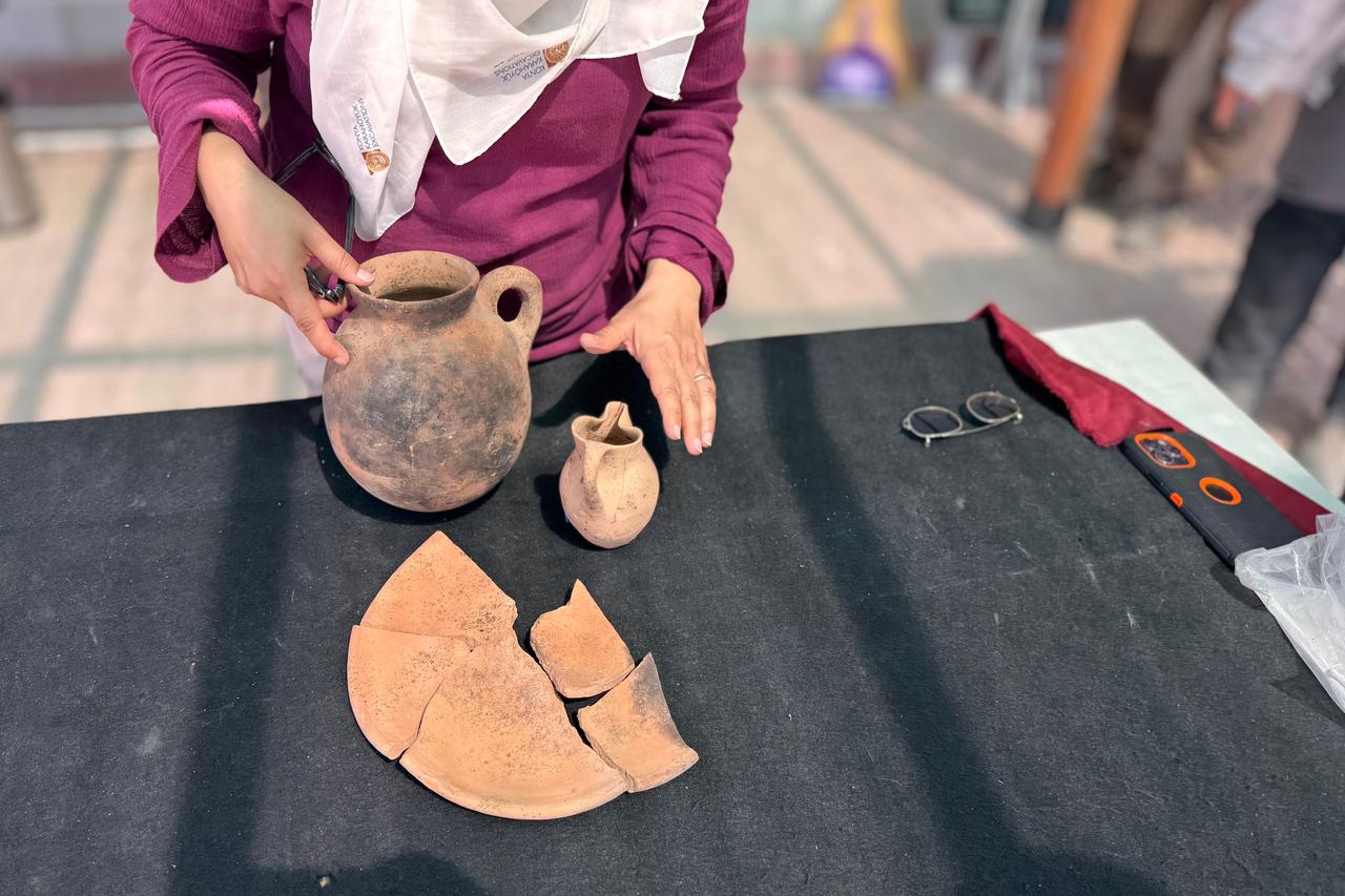 Archaeologist presenting the 3,500-year-old dining set consisting of a jug, trefoil-mouthed jug, and a plate, Sept. 4, 2025. (AA Photo)