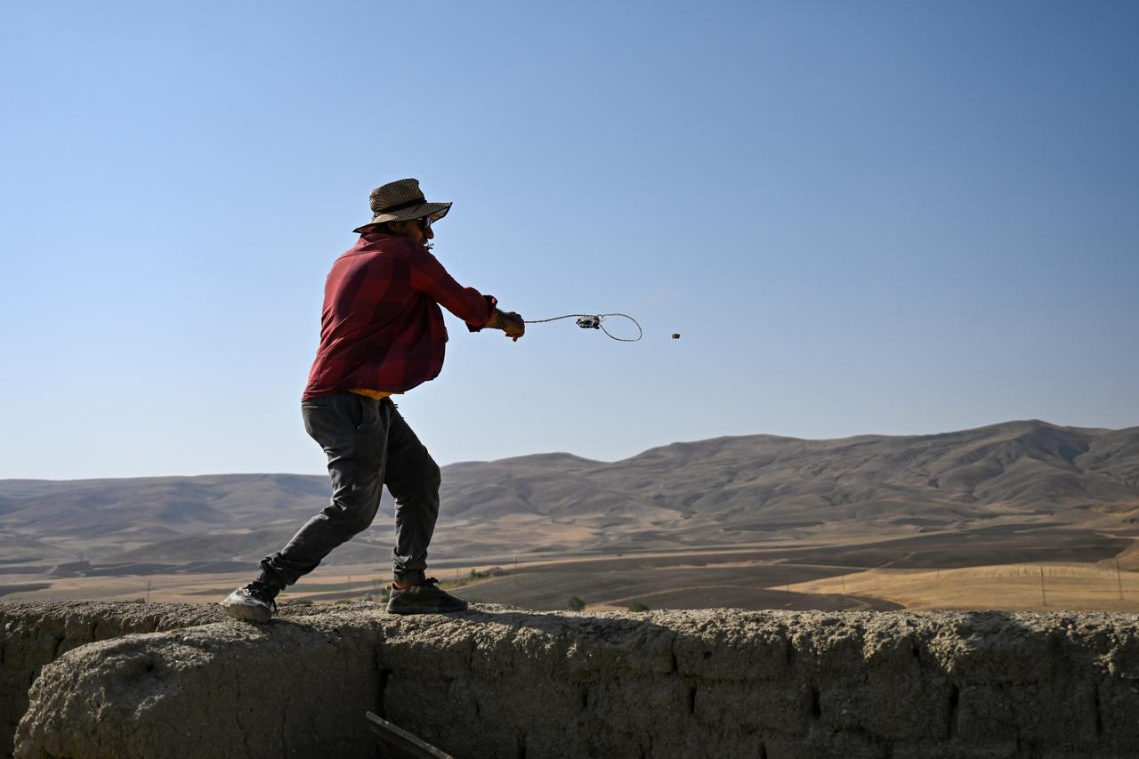 An archaeologist demonstrates the use of sling stones, recently unearthed during excavations at Cavustepe Castle, built by Urartian King Sarduri II in Gurpinar district of Van, Türkiye, August 28, 2025. (AA Photo)