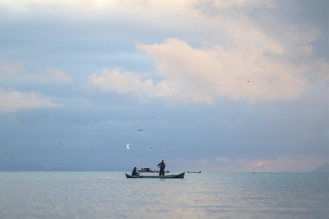 Fishermen at sea casting their lines in the early morning light─country of origin unknown. (Adobe Stock Photo)