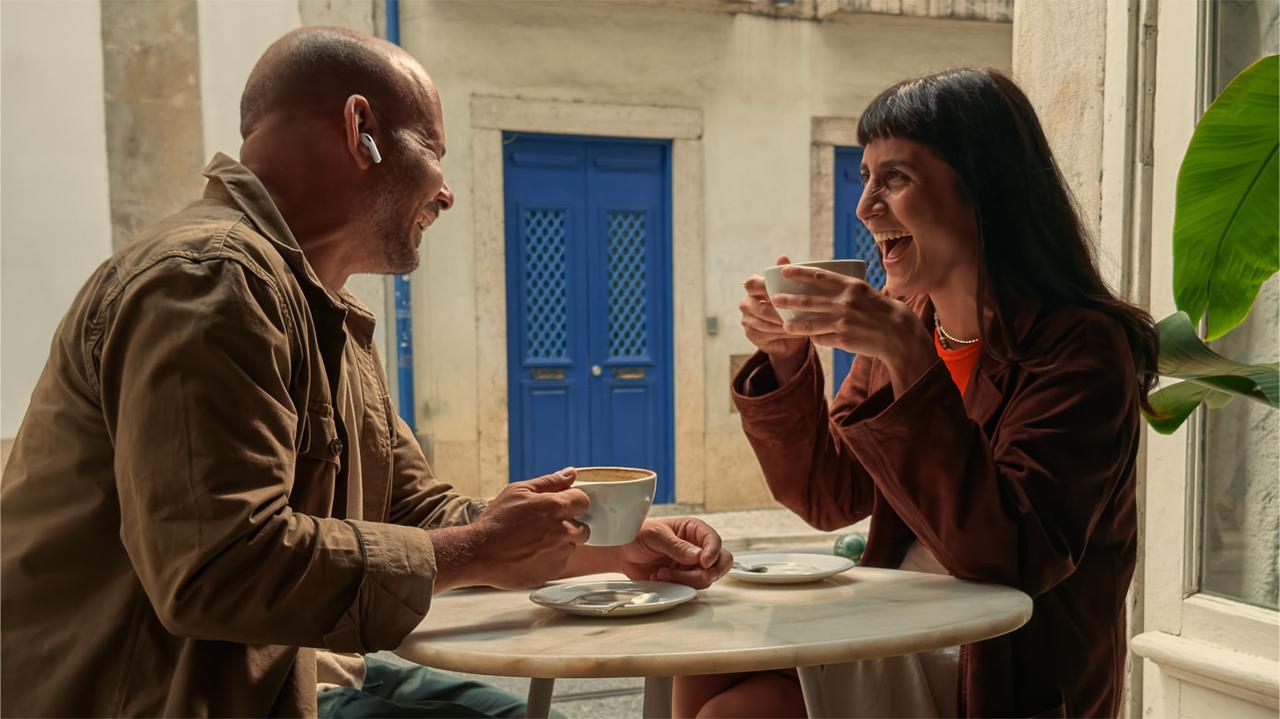 Two people engage in conversation over coffee, with one wearing Apple's new AirPods Pro 3 that feature company's Live Translation capability, accessed on Sep. 11, 2025. (Photo via Apple)