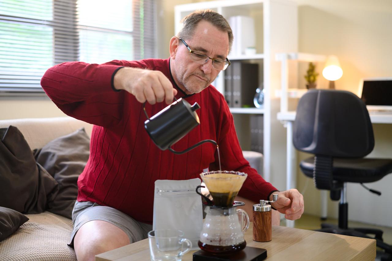 A man prepares pour-over coffee at home. (Adobe Stock Photo)