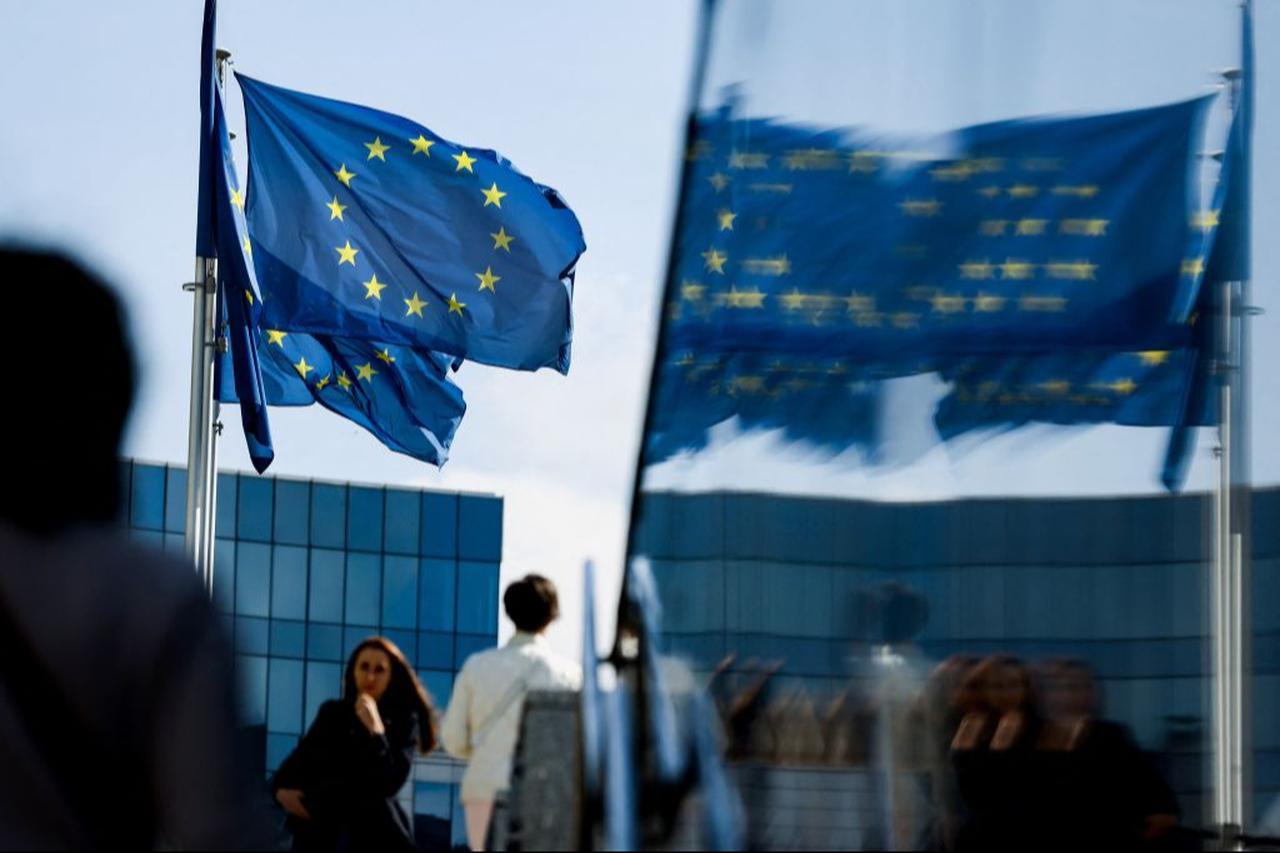 People walk in front of the European Union flag in the area of the EU headquarters in Brussels, September 23, 2021. (AFP Photo)
