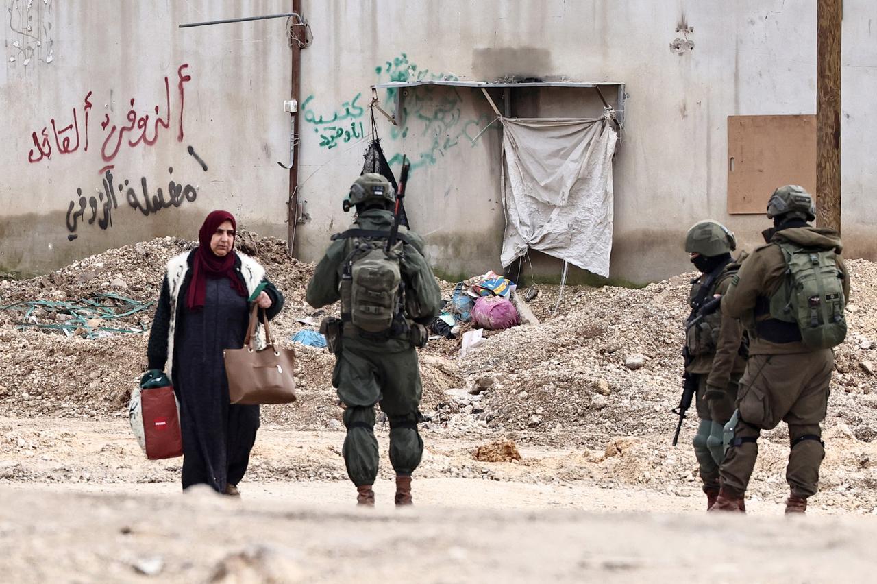 Israeli soldiers speak with a Palestinian woman as she leaves her home for safety during a raid by the army in the Nur Shams refugee camp near Tulkarem in the occupied West Bank on Feb. 11, 2025. (AFP Photo)