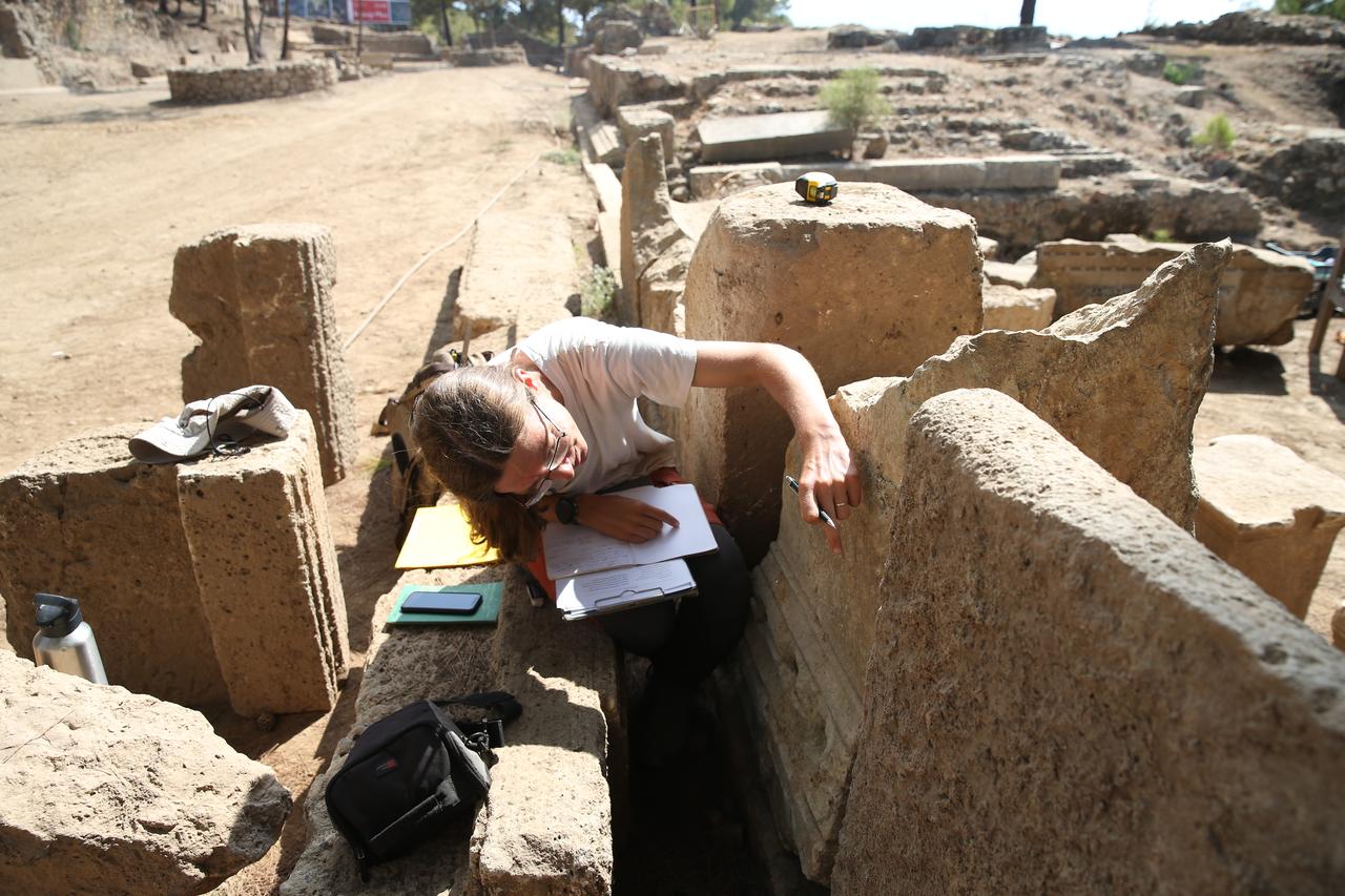 An archaeologist examines stone blocks during excavations at the 1,800-year-old stadium in Syedra, Alanya, Antalya, Türkiye, Sept. 18, 2025. (AA Photo)
