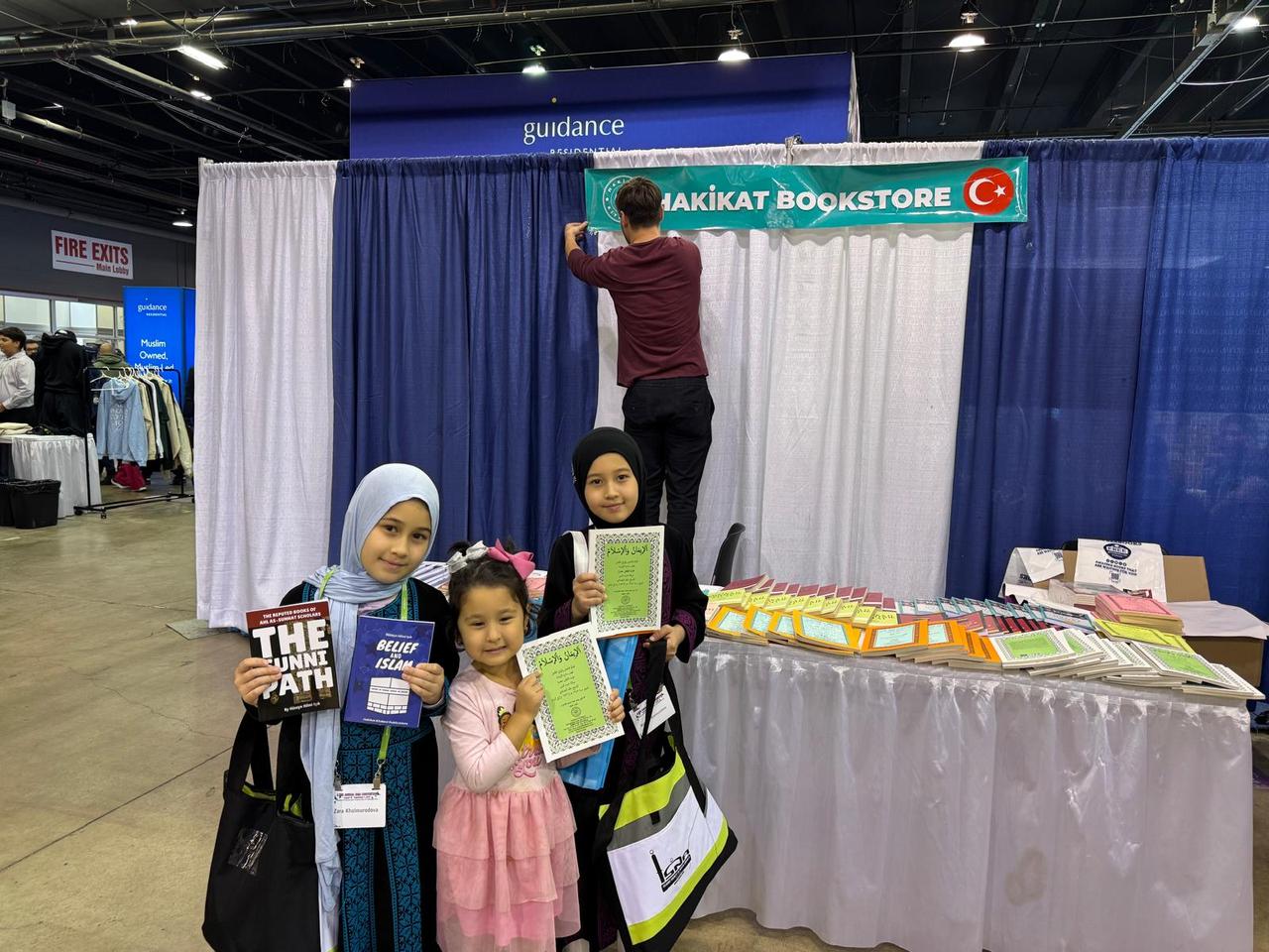 Children pose with books in front of the Hakikat Bookstore booth at the 62nd Annual ISNA Convention 2025 in Chicago, US, Sep. 2, 2025. (Türkiye Today)