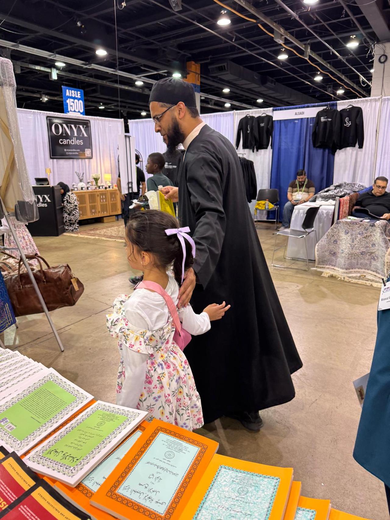 A young girl stands beside a booth in aisle 1500 at the 62nd Annual ISNA Convention 2025 in Chicago, exploring colorful Islamic-themed booklets and candles with her father, Sep. 2, 2025. (Türkiye Today)