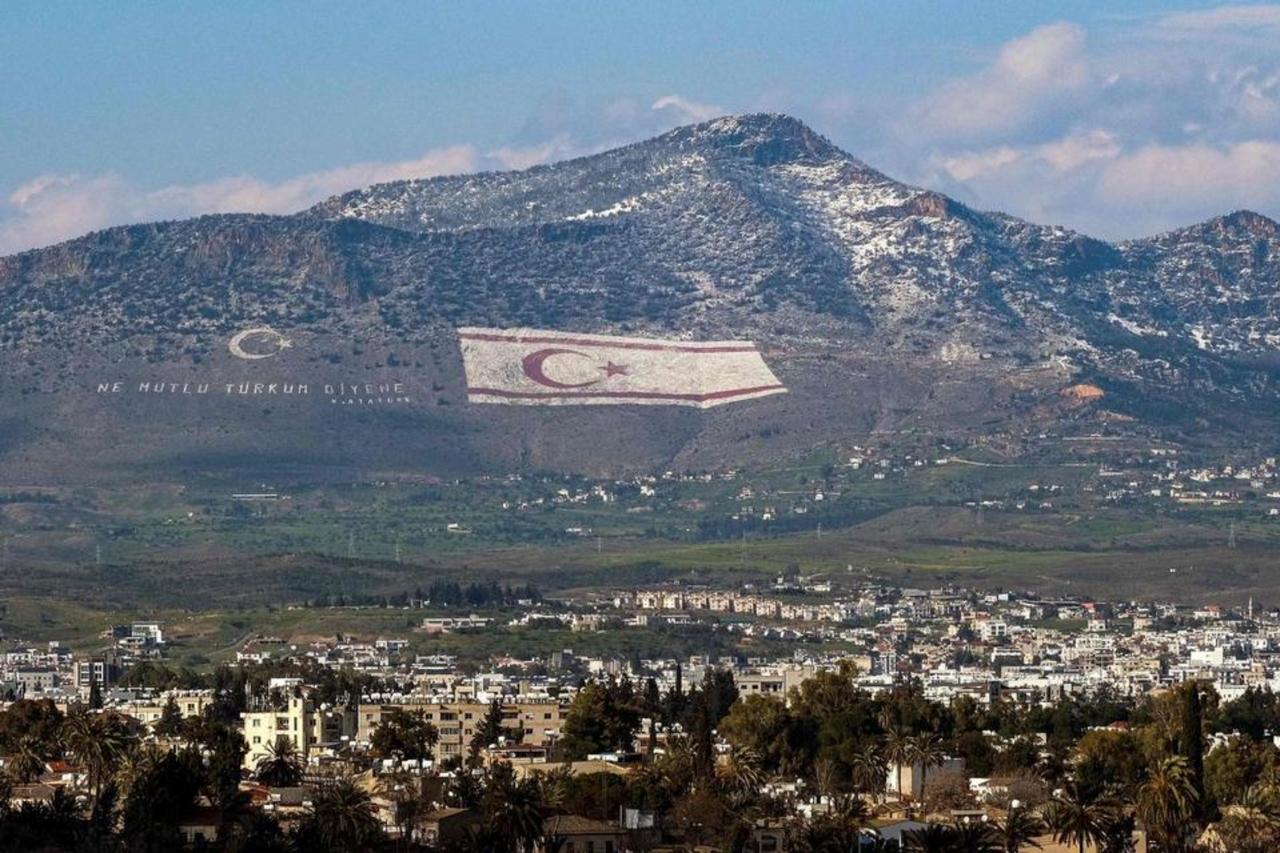 A view of snow covering a portion of Cyprus northern Girne mountain range, above the flag of the Turkish Cyprus (TRNC), Lefkosia on March 13, 2022. (AFP Photo)