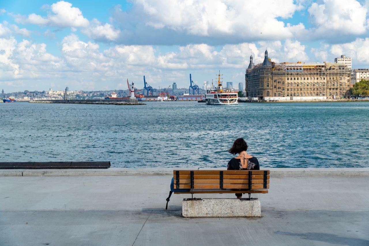 A woman sits on a bench overlooking the Bosphorus near Istanbul’s Haydarpasa Train Station, Türkiye. (Adobe Stock Photo)