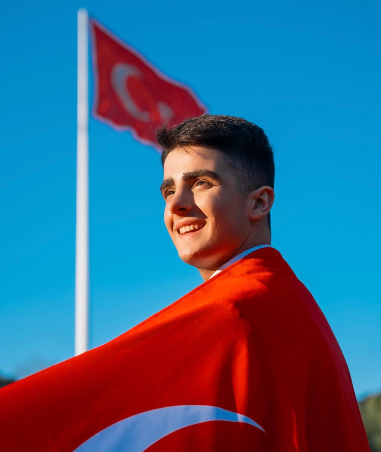 Omar Aliyev draped in a Turkish flag with another flag waving in the background. (Photo via Omar Aliyev's archive)