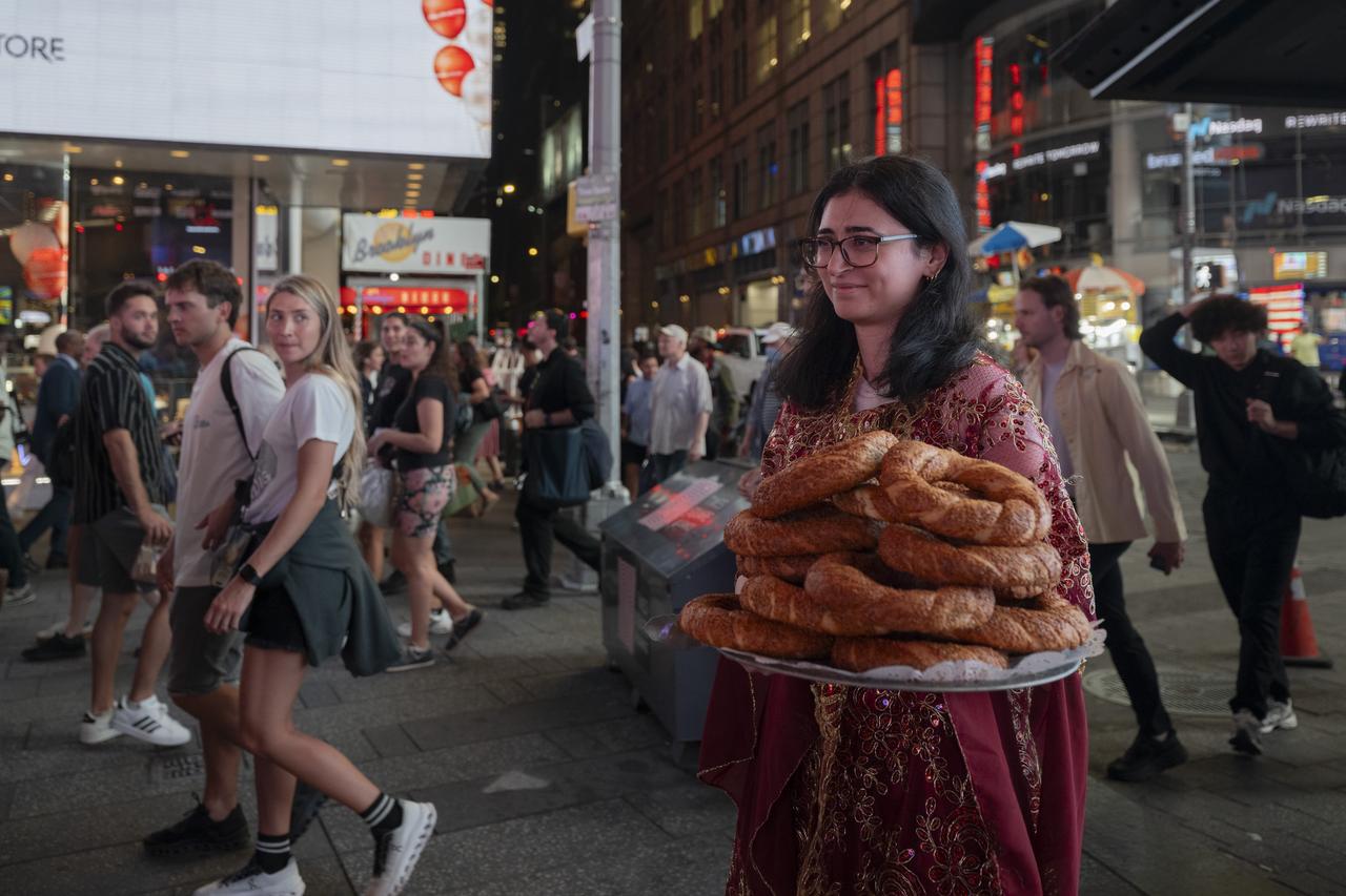 A woman in traditional dress offers Turkish simit, a sesame-crusted bread ring, to passersby during the Anadoludakiler project event at Times Square in New York, US, Sept. 24, 2025. (AA Photo)