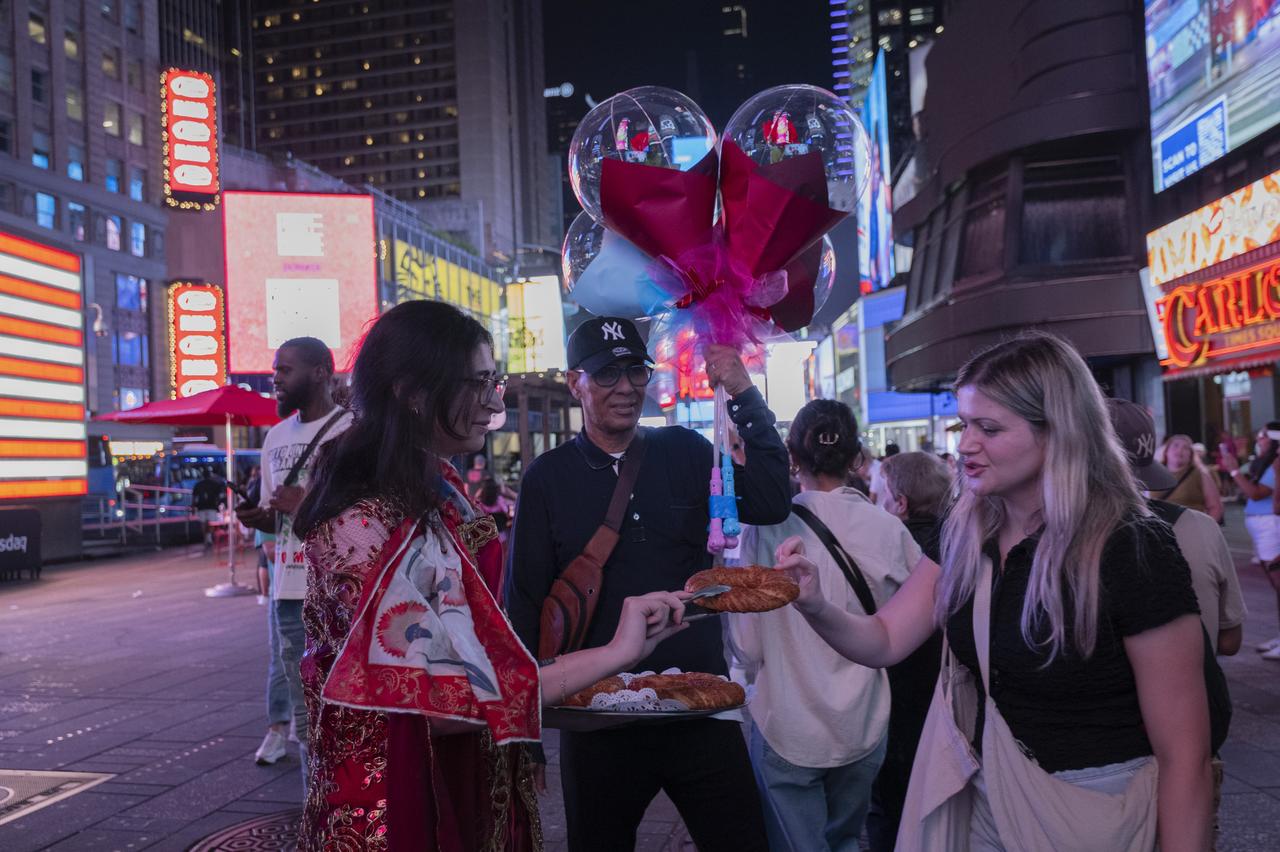 A woman in traditional dress offers Turkish simit, a sesame-crusted bread ring, to passersby during the Anadoludakiler project event at Times Square in New York, US, Sept. 24, 2025. (AA Photo)