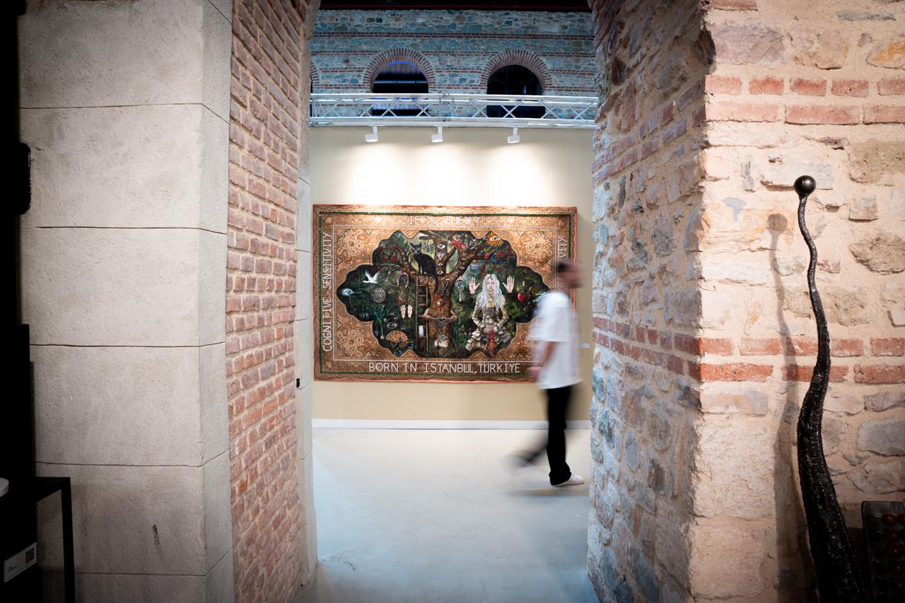 A visitor walks past an artwork reading Born in Istanbul, Türkiye during Contemporary Istanbuls 20th edition, Sept. 24, 2025. (AA Photo)