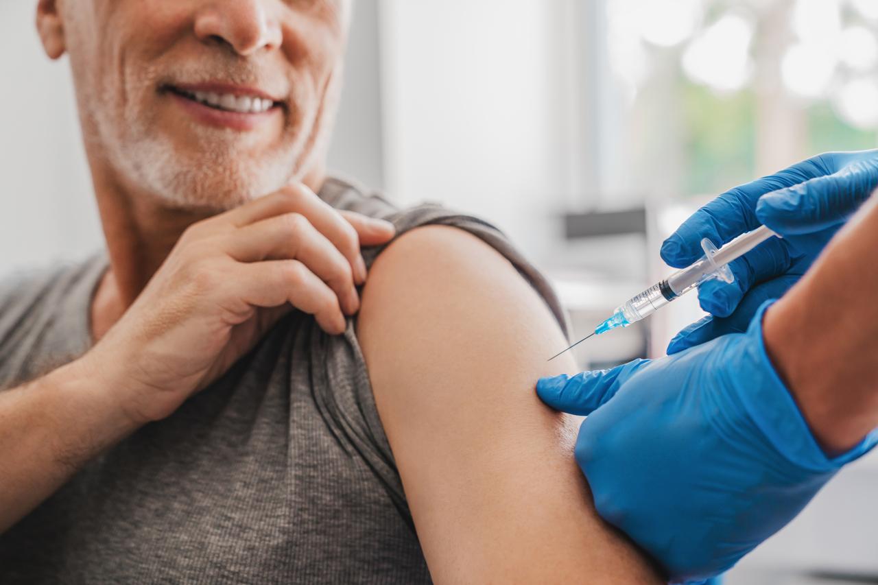 A healthcare professional delivering an injection to an elderly patient in a medical clinic. (Adobe Stock Photo)