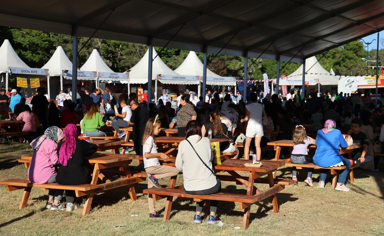 People enjoy meals at picnic tables during the 8th International Taste of Adana Festival in Adana, Türkiye, Oct. 18, 2024. (IHA Photo)