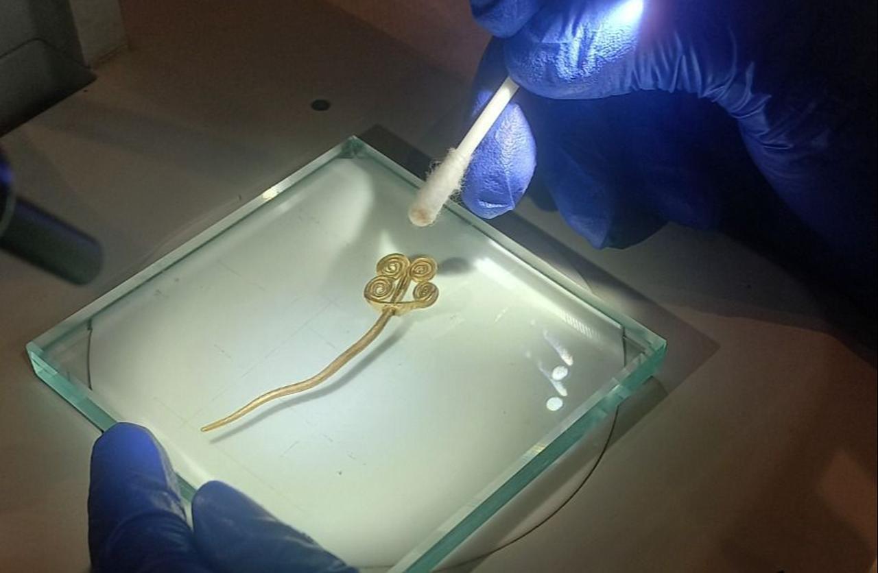 Conservators clean the 4,500-year-old gold brooch found in Troy under a microscope, Sept. 27, 2025. (Photo via Ministry of Culture and Tourism)