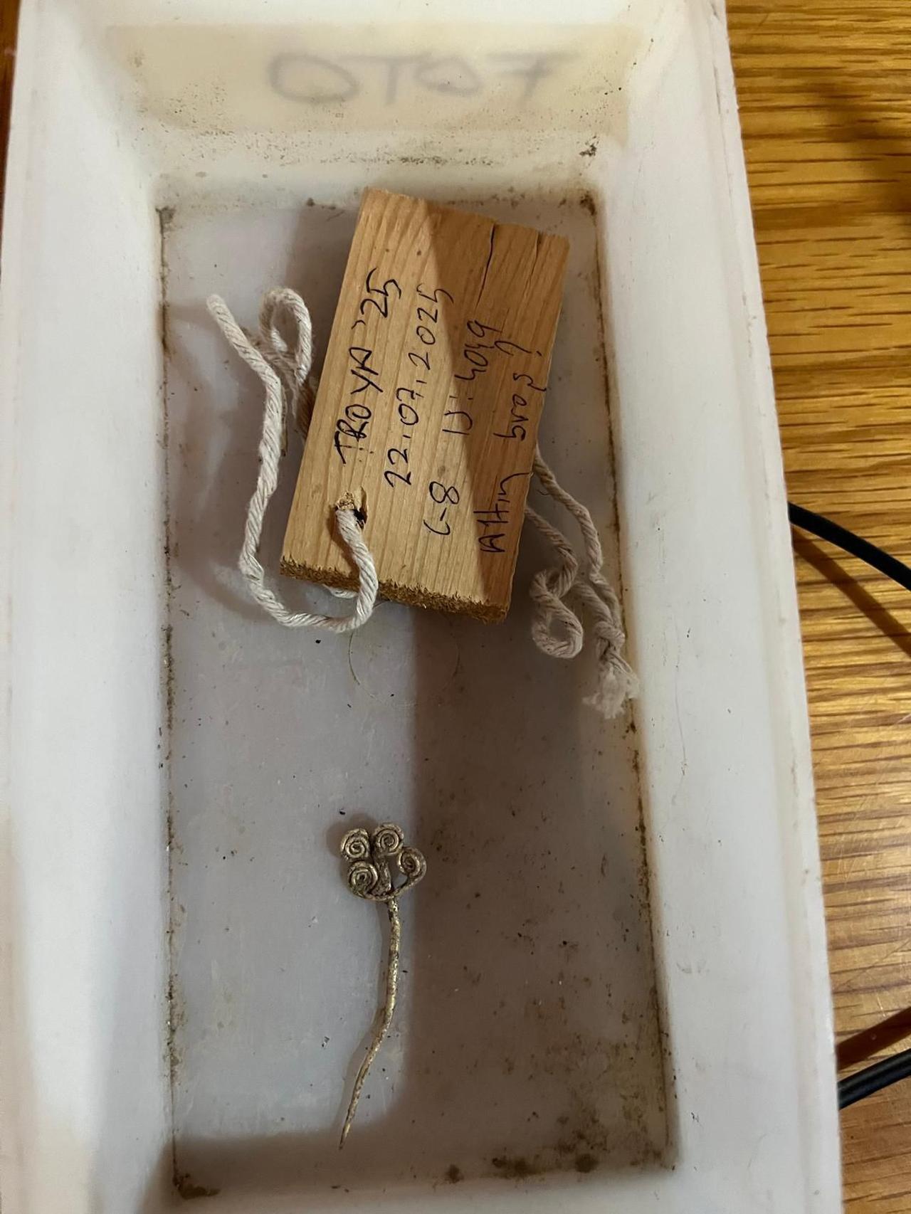 The gold brooch stored with its excavation label after being unearthed in Troy, Sept. 27, 2025. (Photo via Ministry of Culture and Tourism)